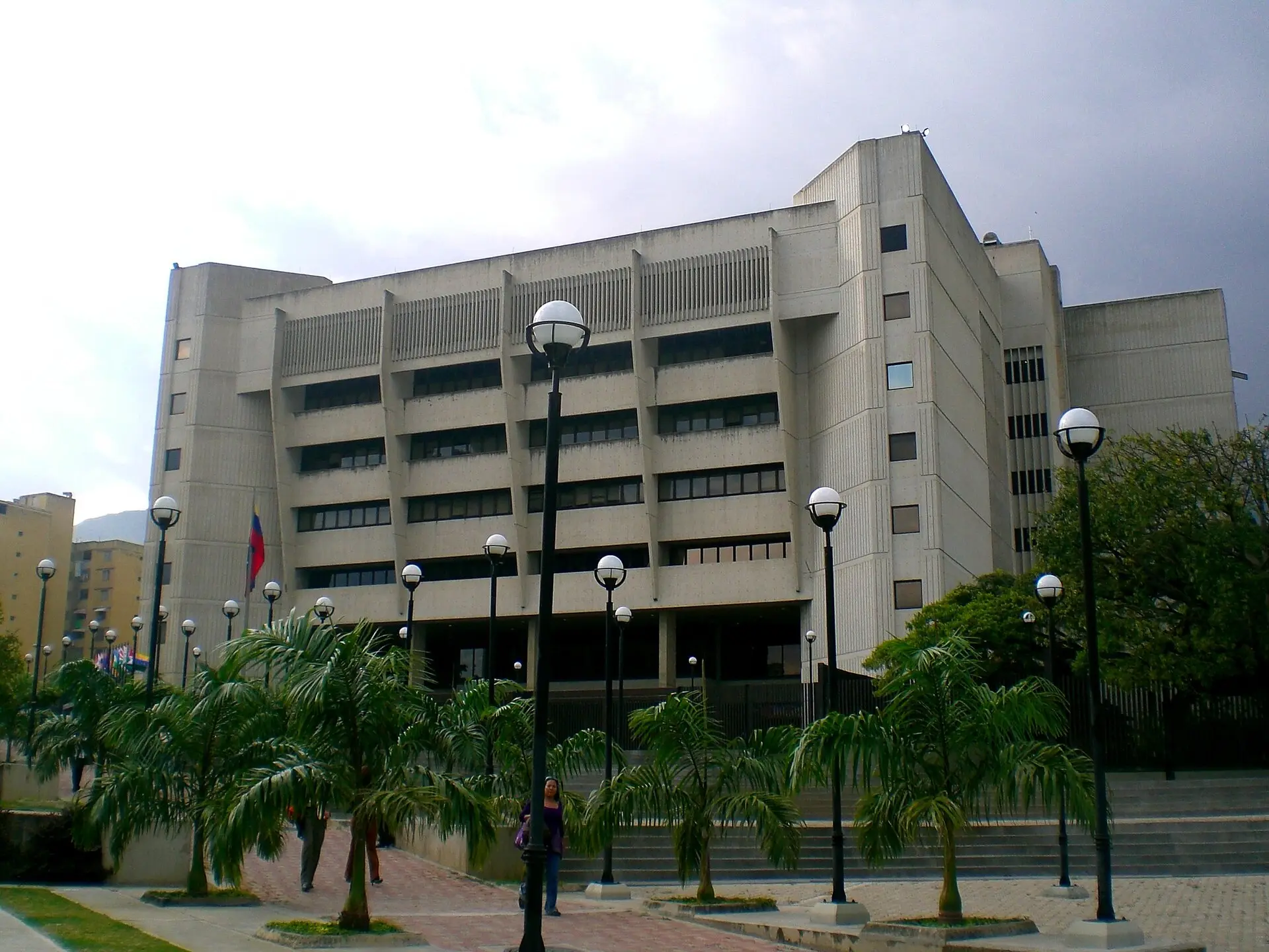 La sede de concreto del Tribunal Supremo de Justicia de Venezuela en Caracas, con palmeras y faroles al frente.