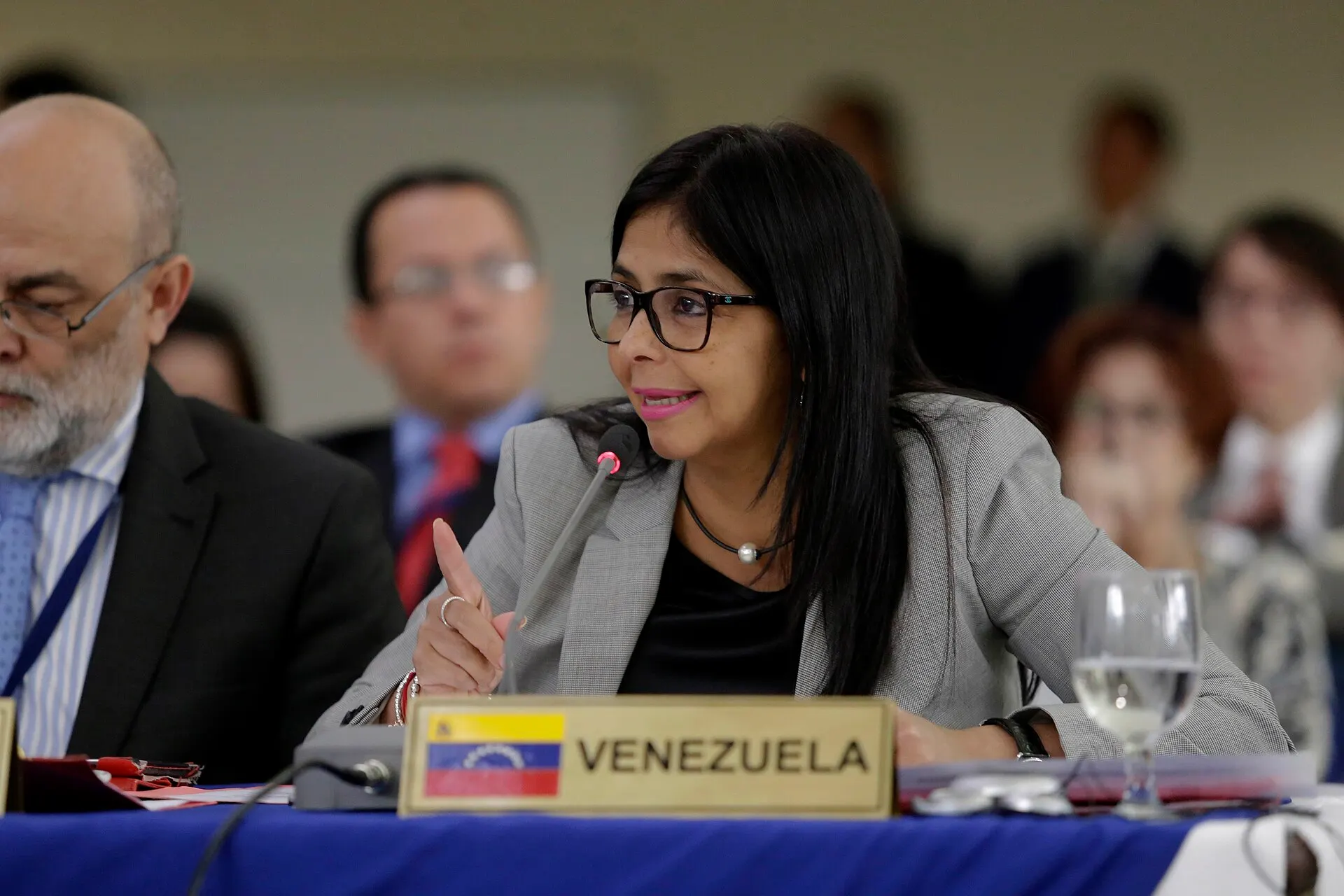 Delcy Rodríguez speaks into a microphone behind a 'Venezuela' nameplate at a meeting of Latin American foreign ministers.
