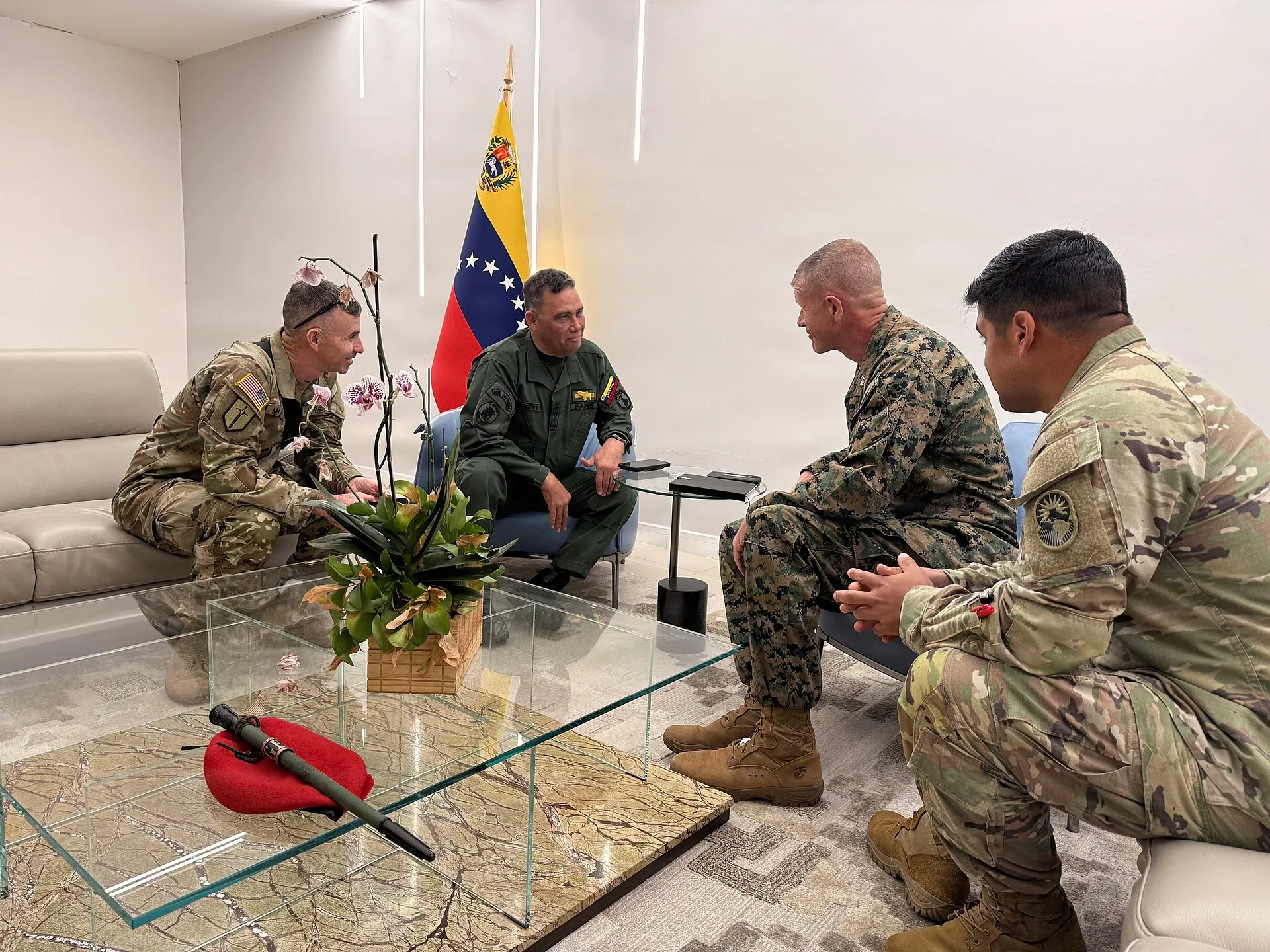 General Gustavo González López, in green uniform beside a Venezuelan flag, meets seated U.S. military officers.