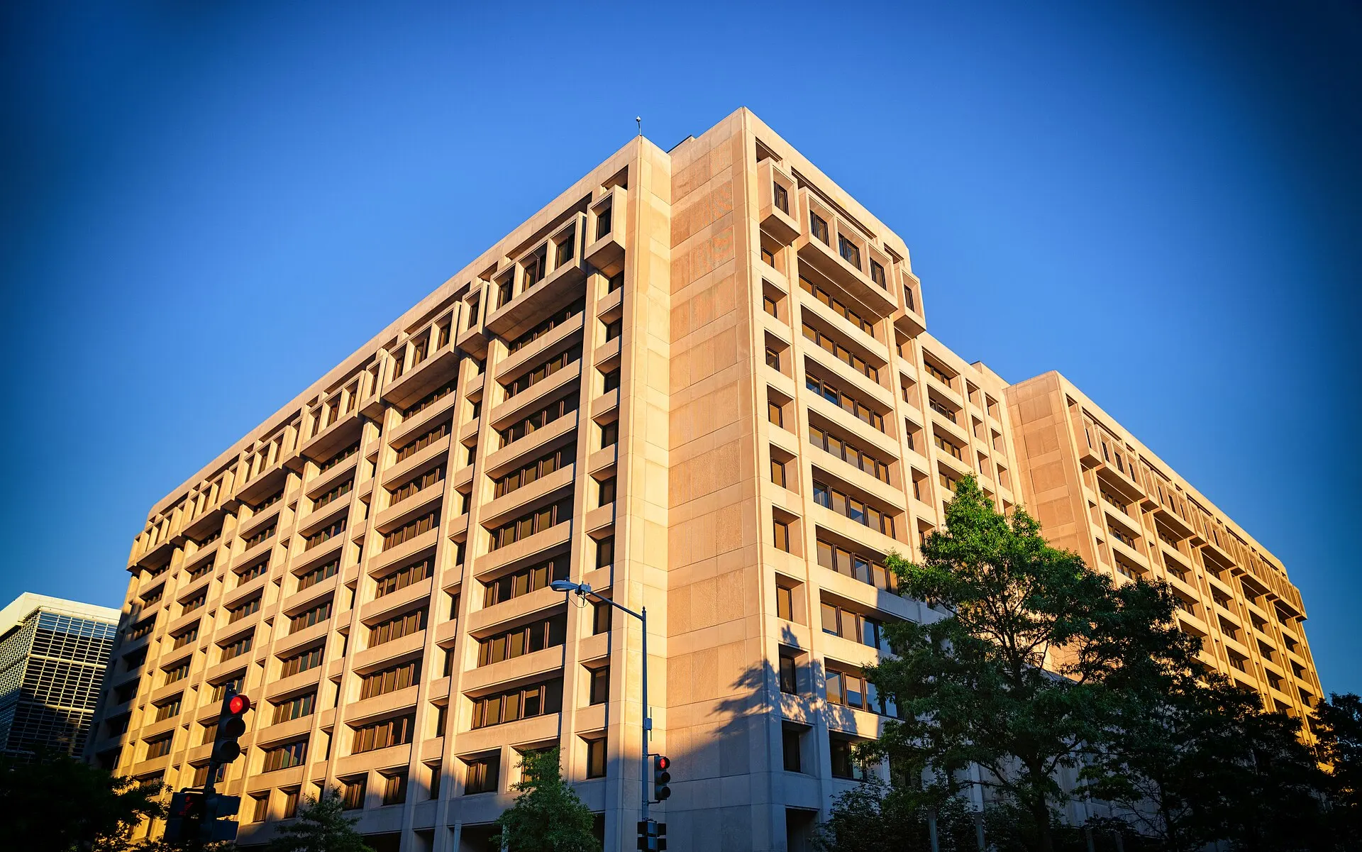 El alto edificio beige de la sede del Fondo Monetario Internacional en Washington D. C., bajo un cielo azul despejado.