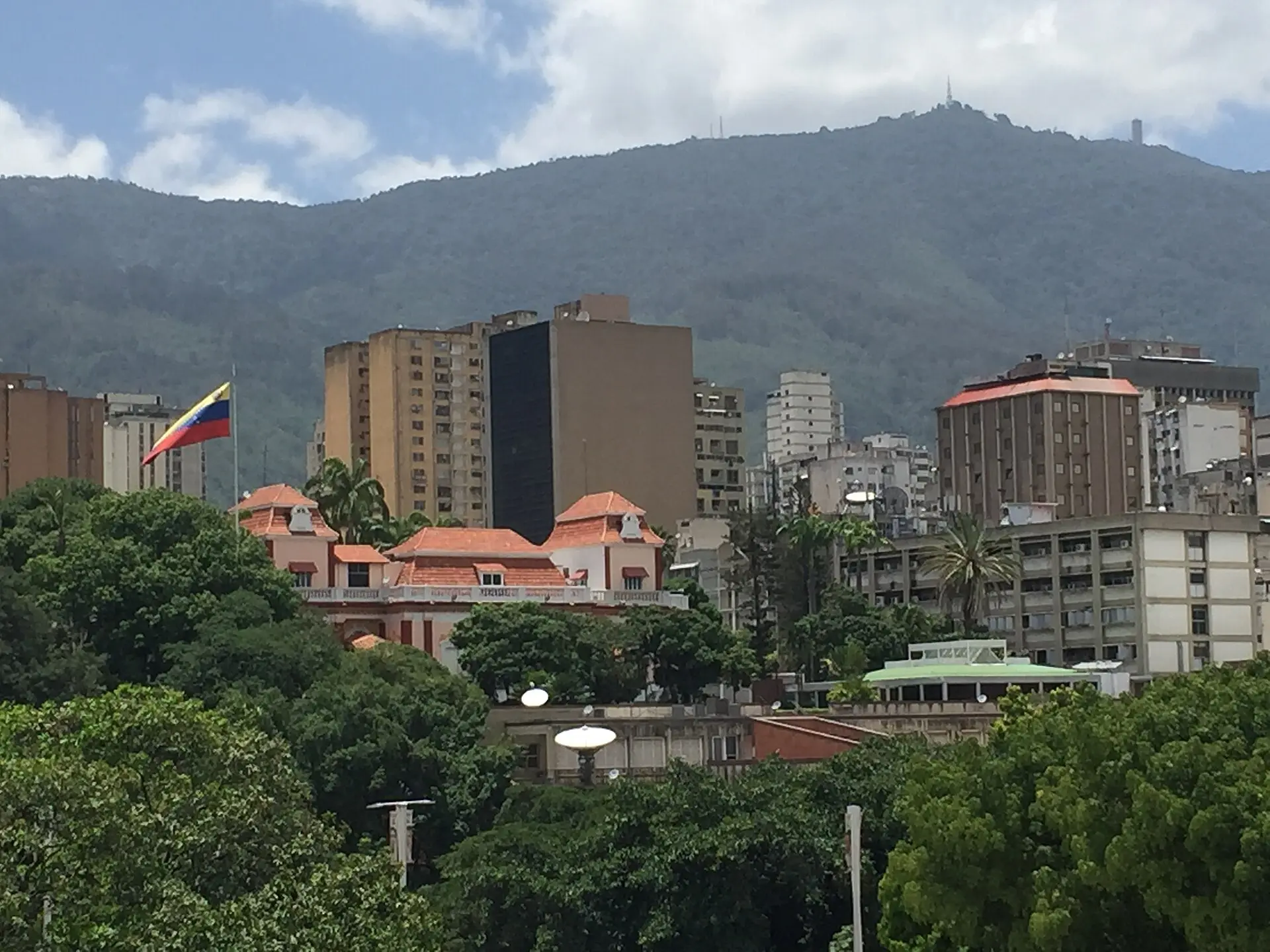 The Miraflores presidential palace in Caracas, flying the Venezuelan flag, with the Ávila mountain behind.