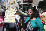 Una docente con megáfono protesta en Caracas junto a un cartel que pregunta cómo enseñar y aprender con hambre en el aula.