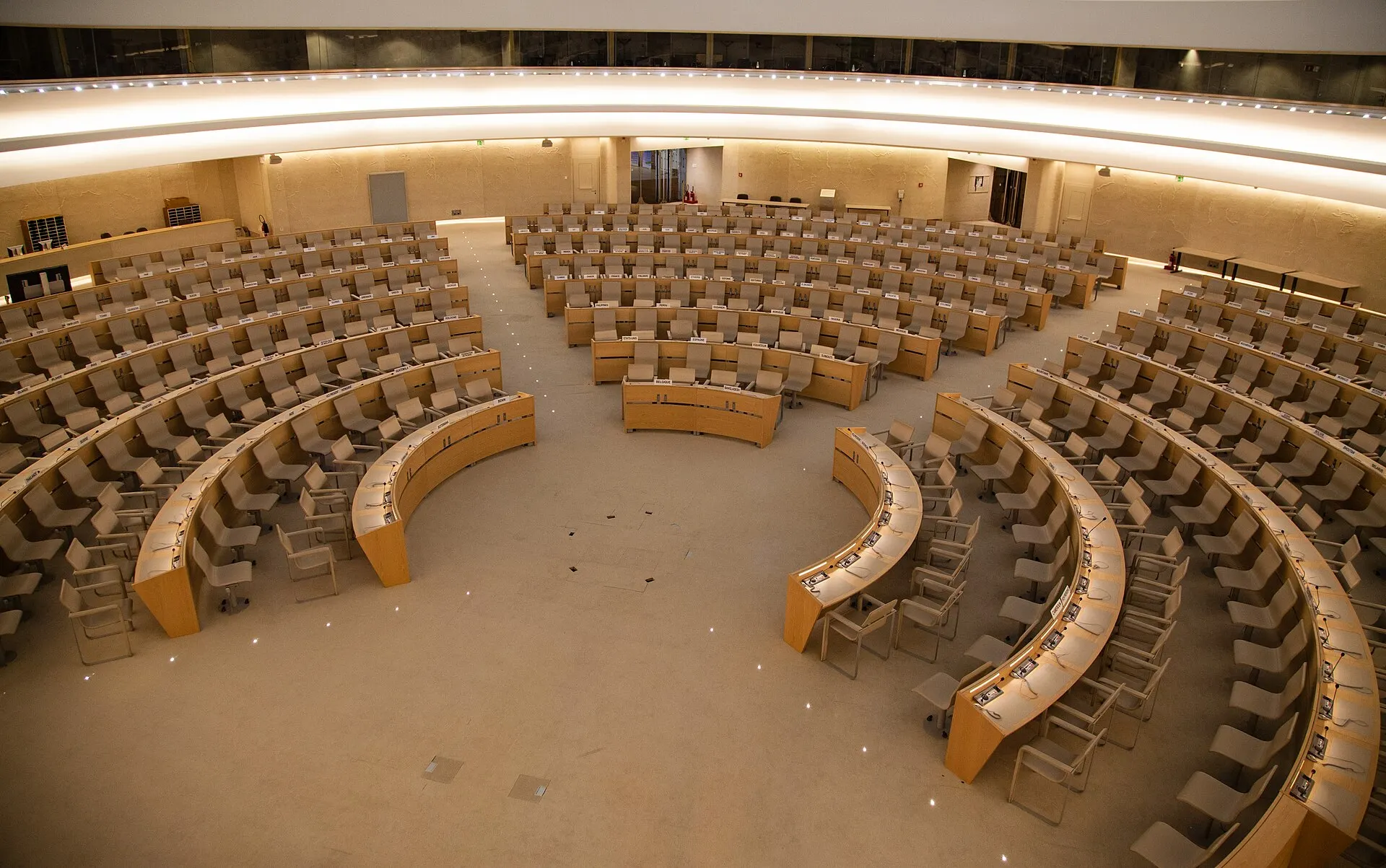 Empty curved rows of delegate desks fill the Human Rights Council chamber at the Palace of Nations in Geneva.