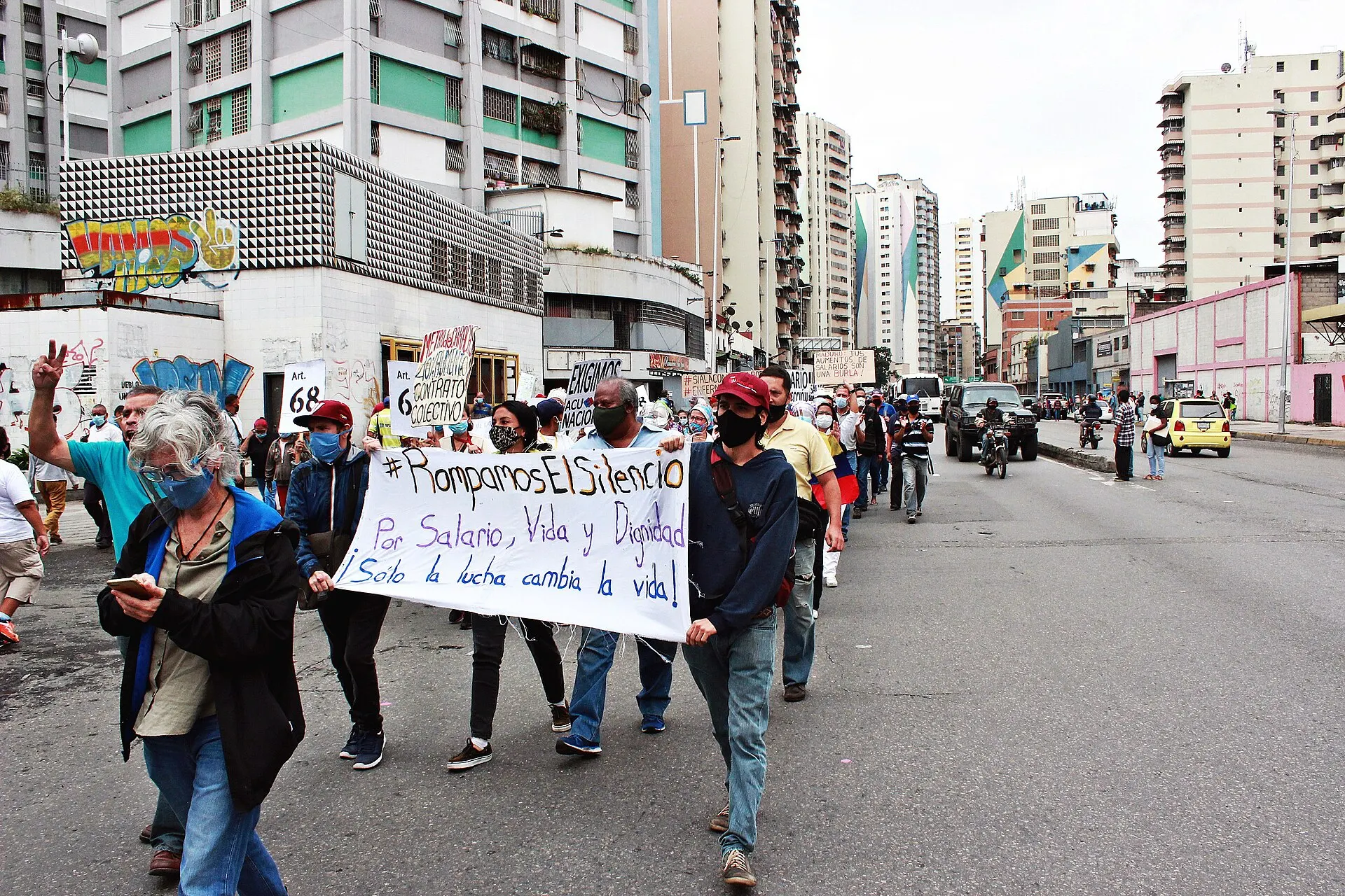 Trabajadores marchan por una avenida de Caracas detrás de una pancarta que exige salario, vida y dignidad.
