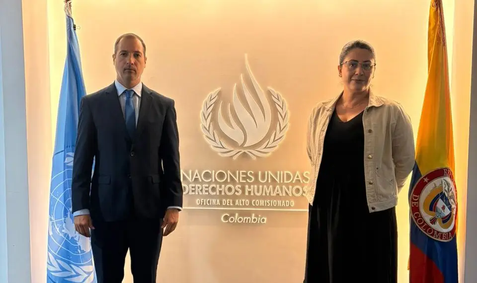 Two VP Colombia representatives at the UN Human Rights office in Colombia, beside UN and Colombian flags.